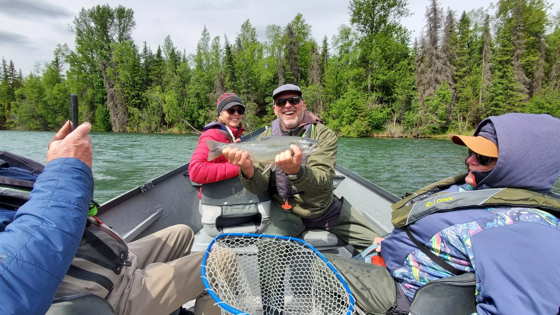 Fly fishing clients in the drift boat with a fresh catch on the Kenai River near Cooper Landing, Alaska