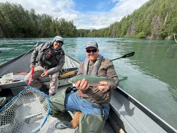 Client holding a rainbow trout beside guide Ron Doebler in a Kenai River canyon, Alaska