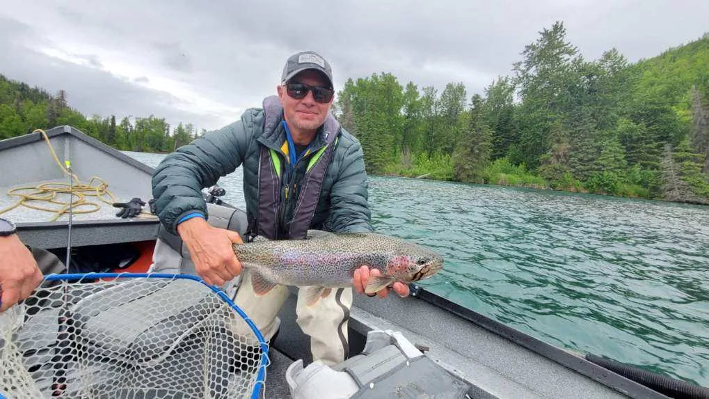Angler with a rainbow trout aboard a drift boat on the upper Kenai River, Alaska